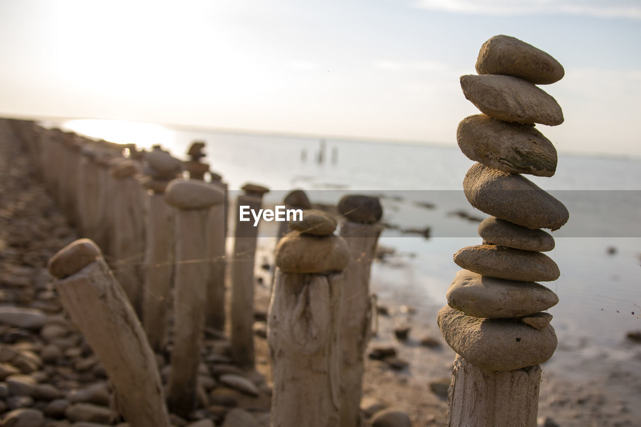Close-up of wooden posts on sea against sky