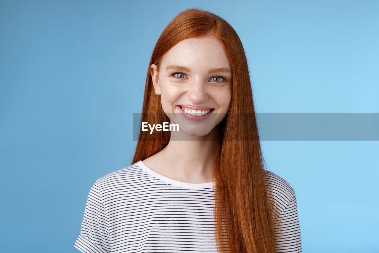 Redhead woman smiling against blue background