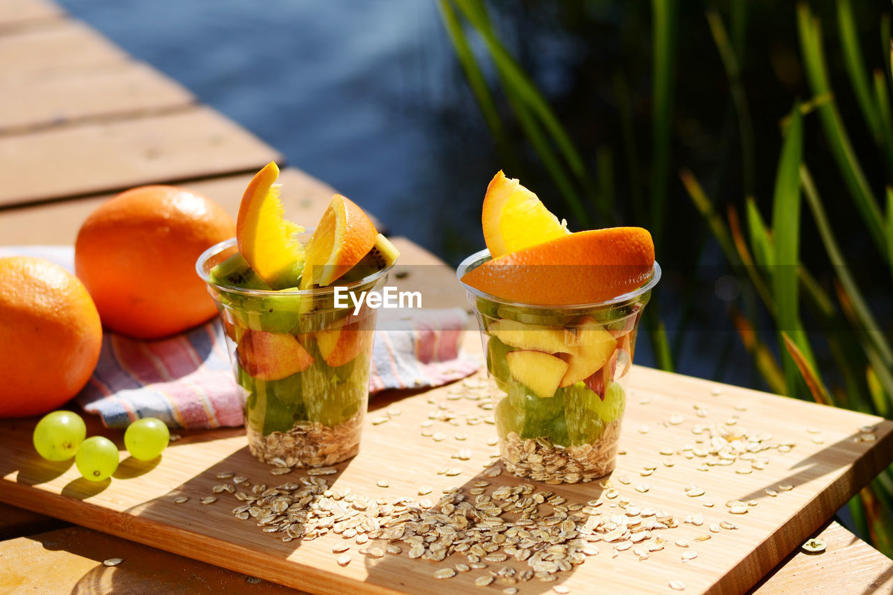Fruits in disposable cups on cutting board over table