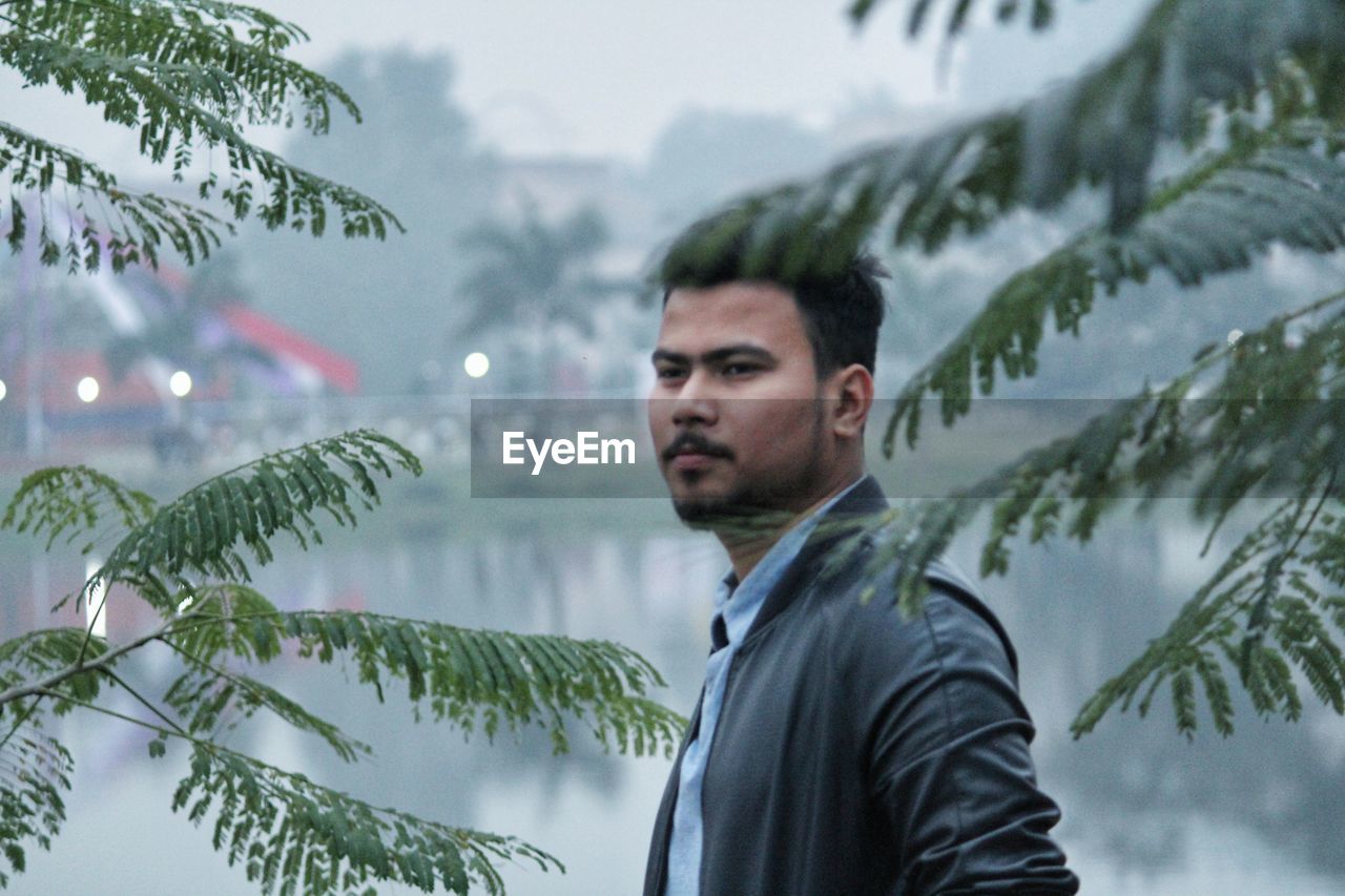 Young man looking through trees during winter