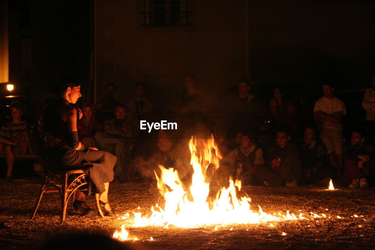 PEOPLE SITTING BY BONFIRE