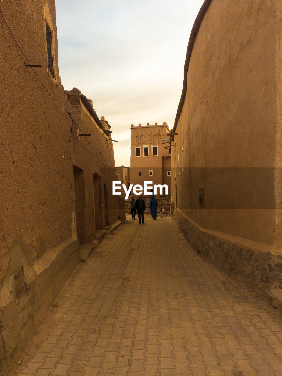 PEOPLE WALKING ON STREET AMIDST BUILDINGS