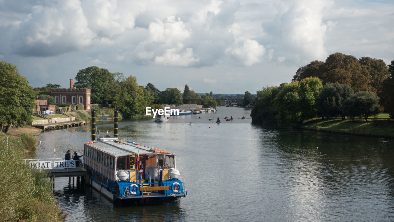 BOAT SAILING IN RIVER AGAINST SKY