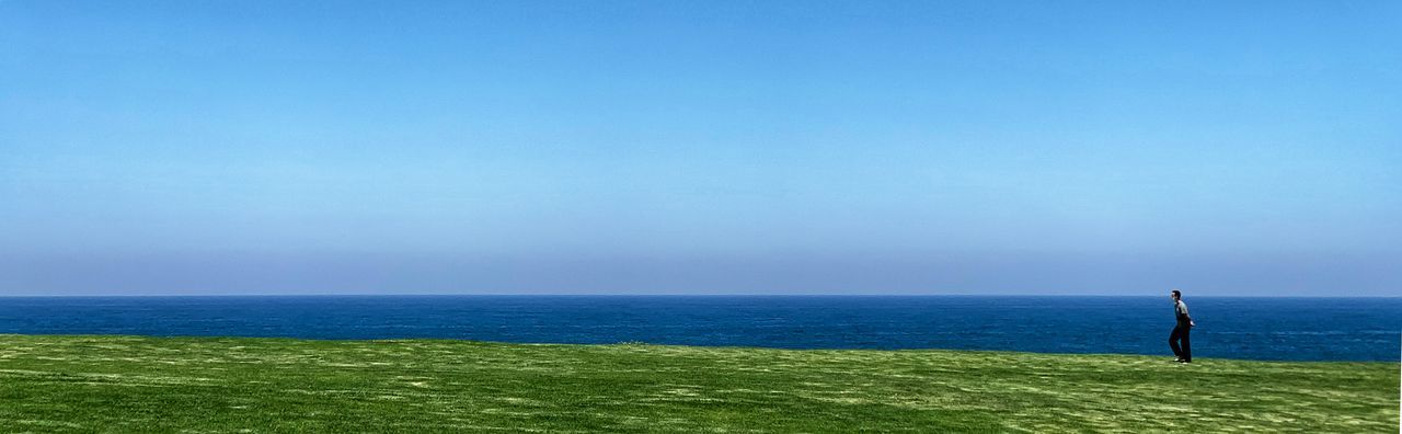 MAN STANDING IN SEA AGAINST SKY