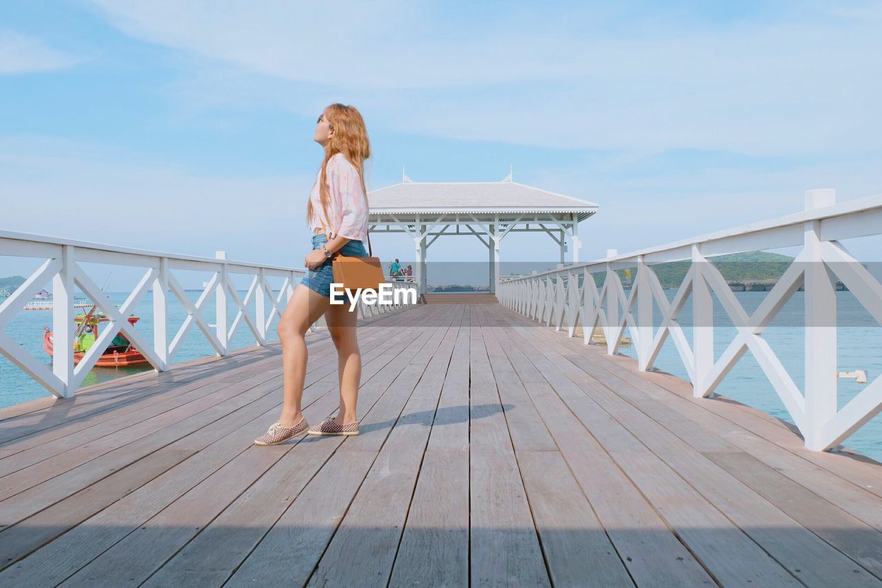 Full length of woman standing on pier over sea against sky