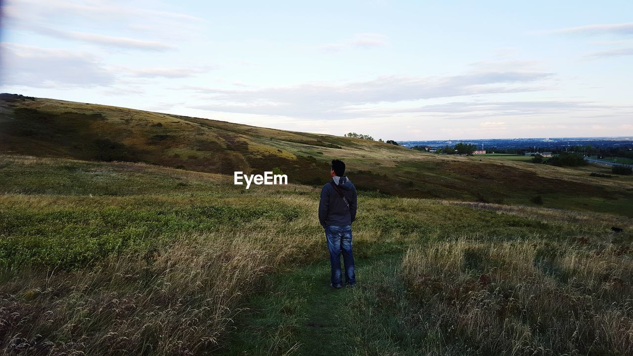 Rear view of man standing on land at sunset