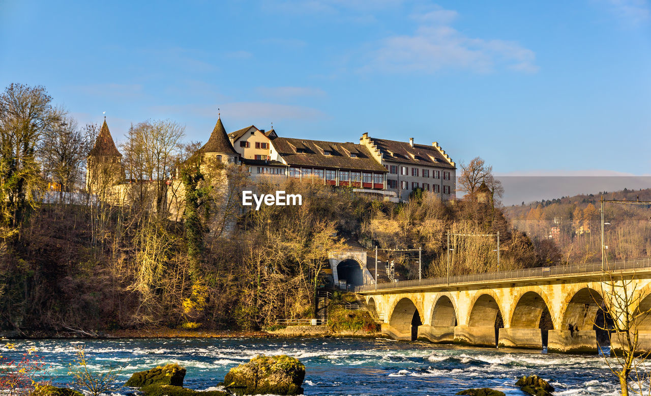 ARCH BRIDGE OVER RIVER AGAINST BUILDINGS