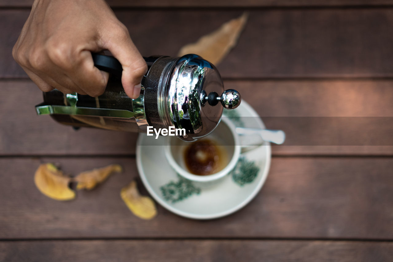 Pour french coffee into a cup. glass on a wooden table