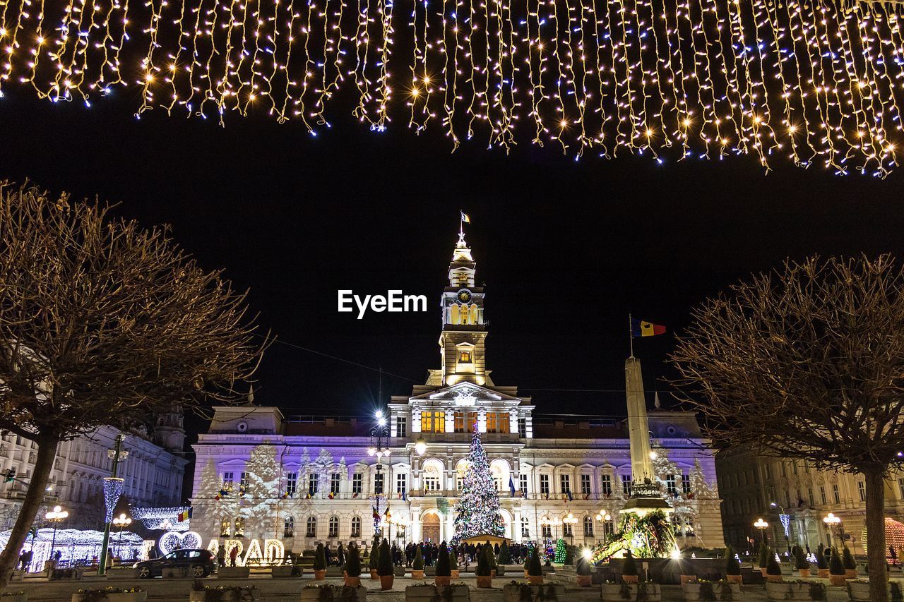 ILLUMINATED CHRISTMAS TREE AGAINST BUILDING AT NIGHT