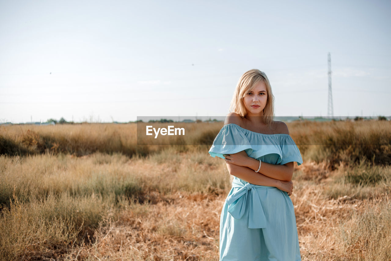 Portrait of teenage girl wearing dress standing on land against sky