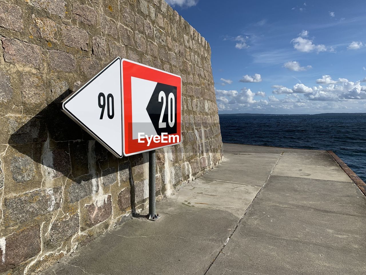 Warning sign by sea against sky
