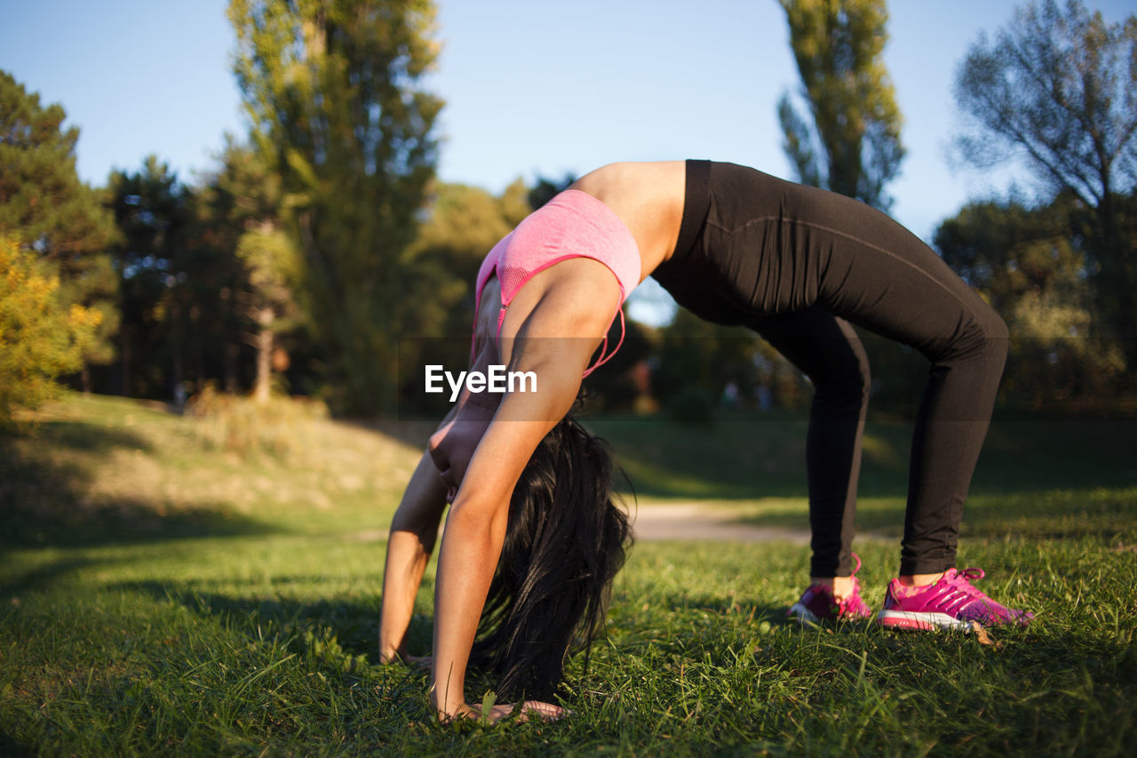 Young girl practices yoga in the park on the grass.