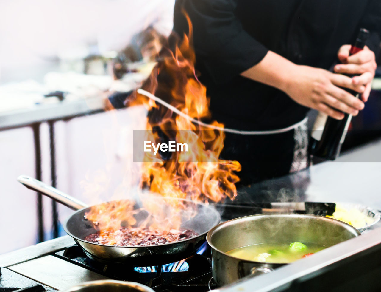 midsection of man preparing food on stove