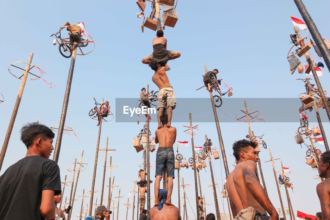 LOW ANGLE VIEW OF PEOPLE LOOKING AWAY AGAINST CLEAR SKY