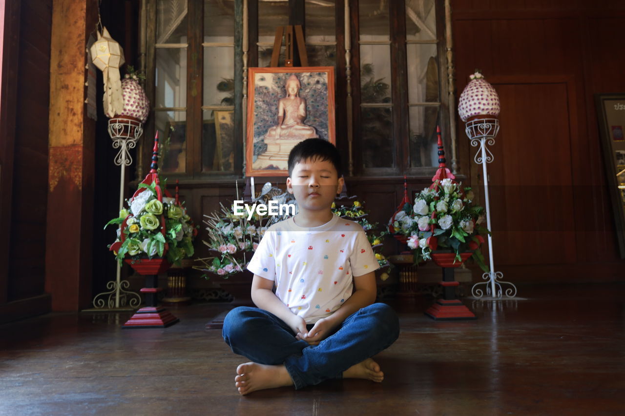 Portrait of boy meditate on floor