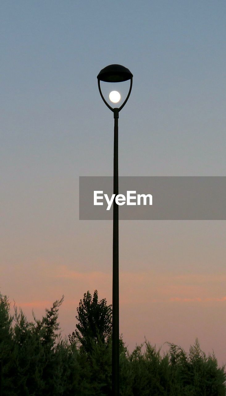 Illuminated street light against sky during sunset