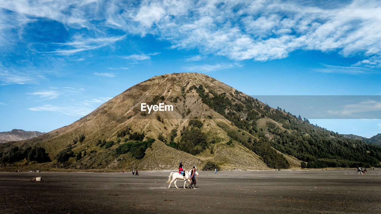 People riding horses on mountain against sky