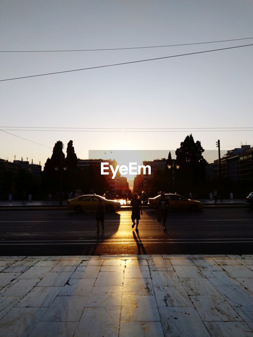 PEOPLE ON STREET IN CITY AGAINST SKY AT SUNSET