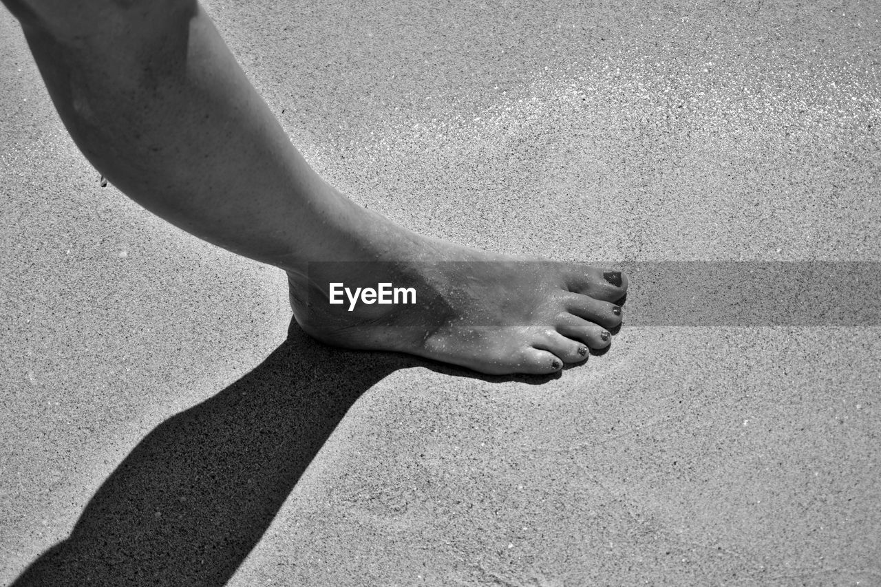 Low section of woman on sand at beach