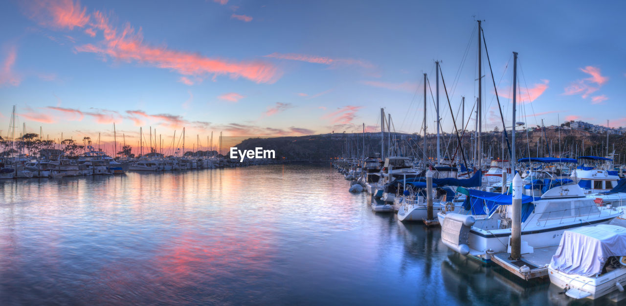 SAILBOATS MOORED AT HARBOR AGAINST SKY