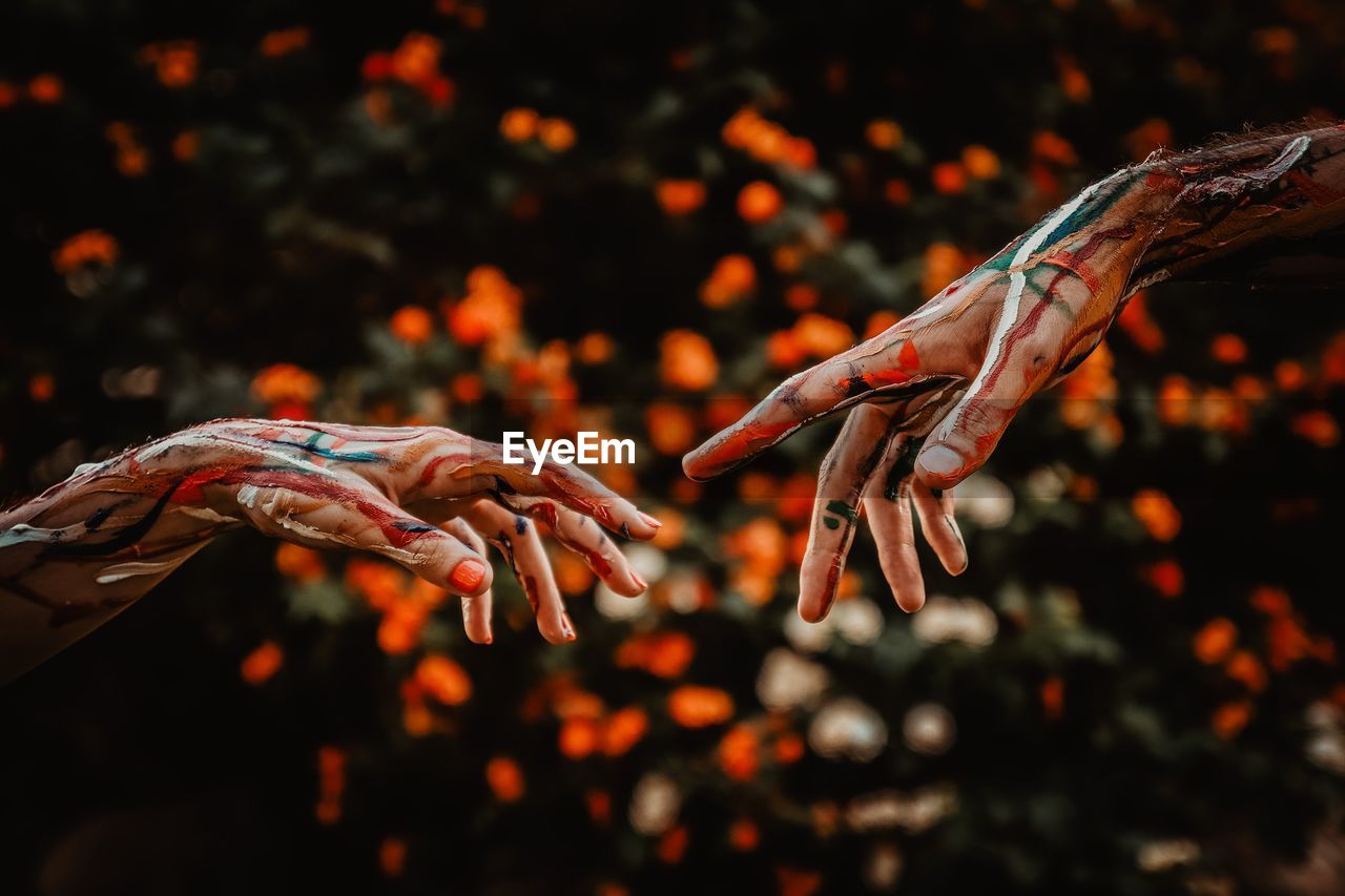 Close-up of cropped painted hands against trees