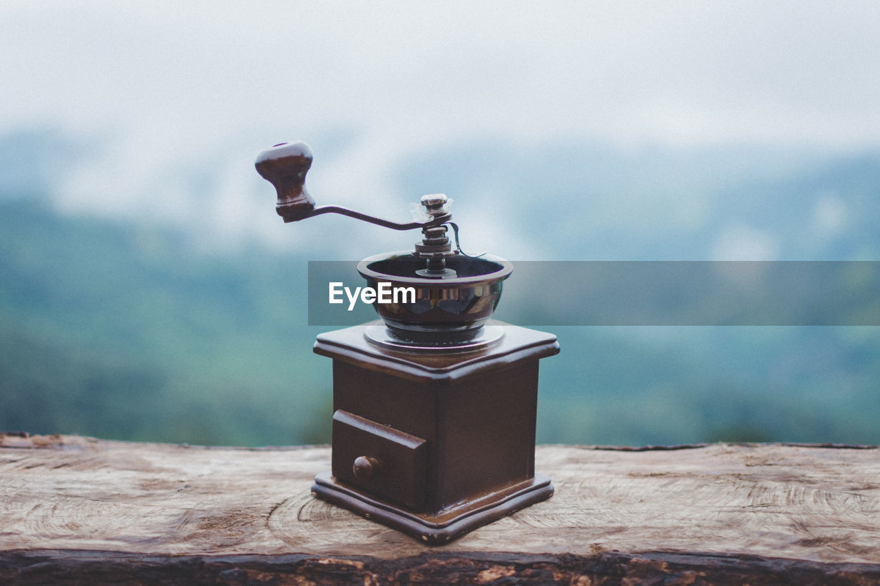 Close-up of coffee grinder on table against sky