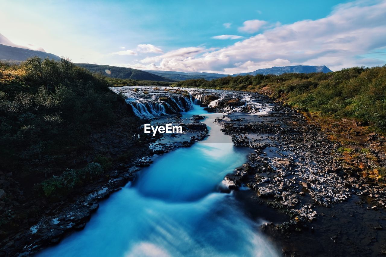 Scenic view of river amidst mountains against sky