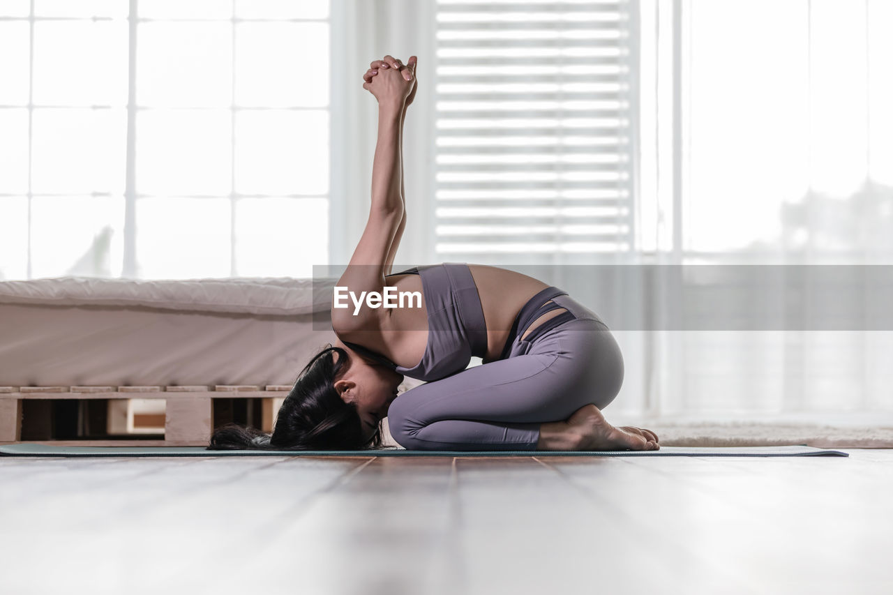 Woman doing yoga at home during day