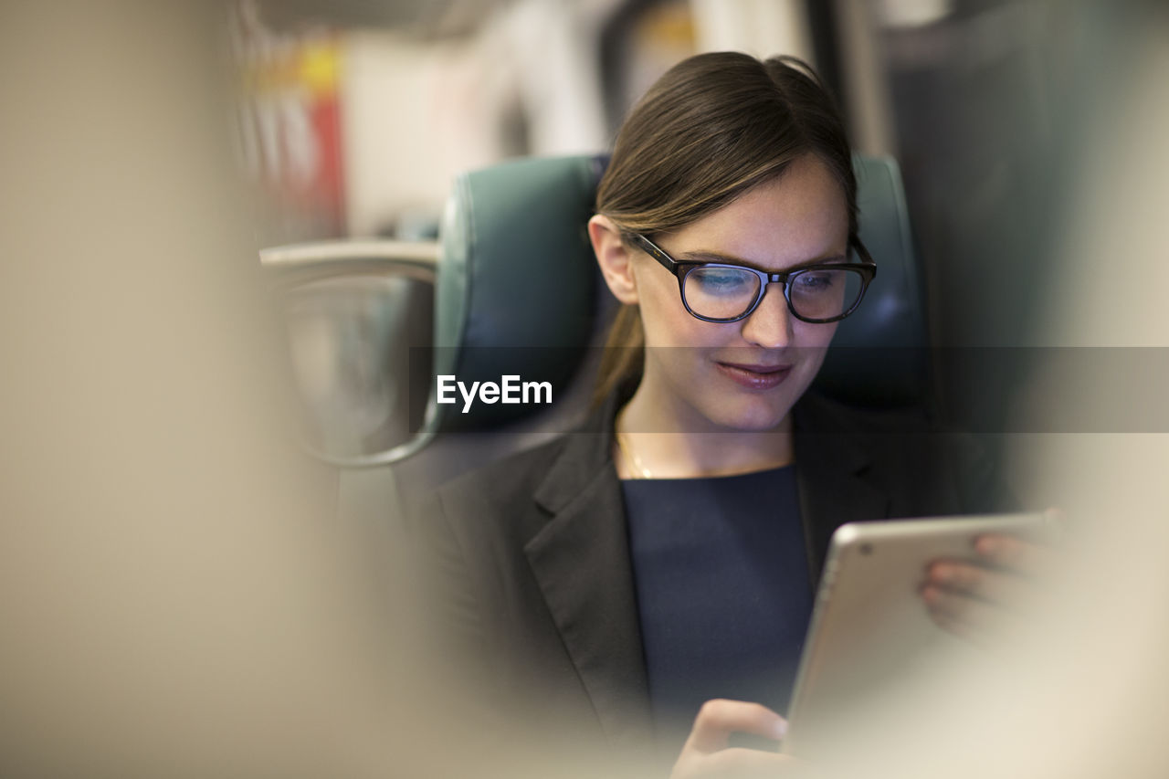 Happy businesswoman using tablet while traveling in subway train