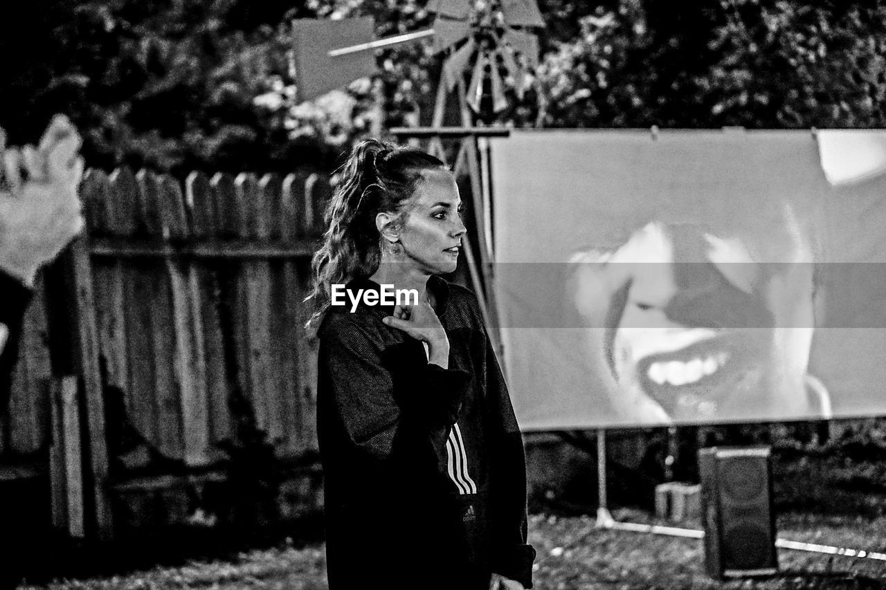 Thoughtful woman standing against projection screen in yard