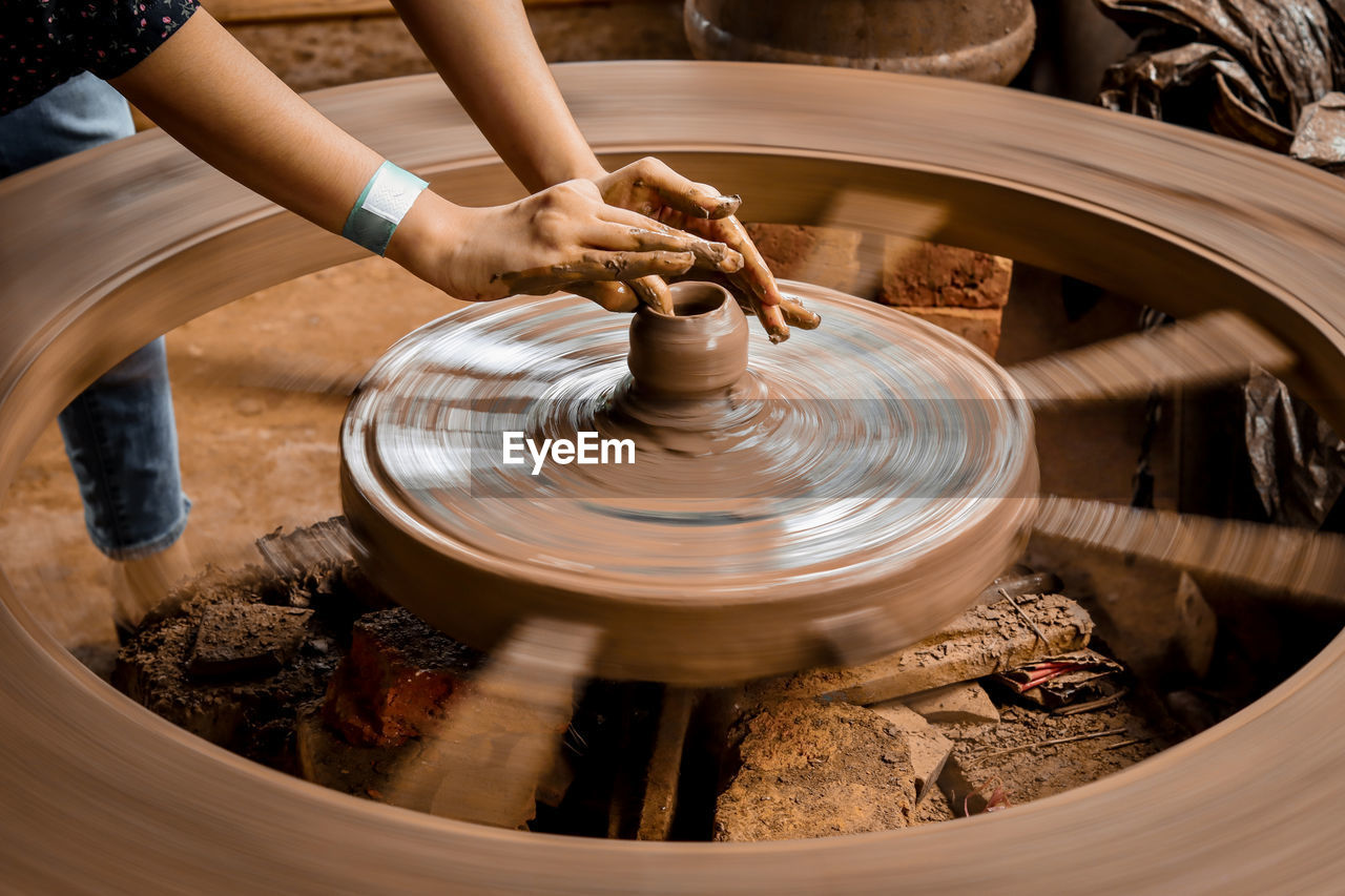 A slow shutter shot of a potter hand making a pot from a pottery wheel at hubli, karnataka, india.