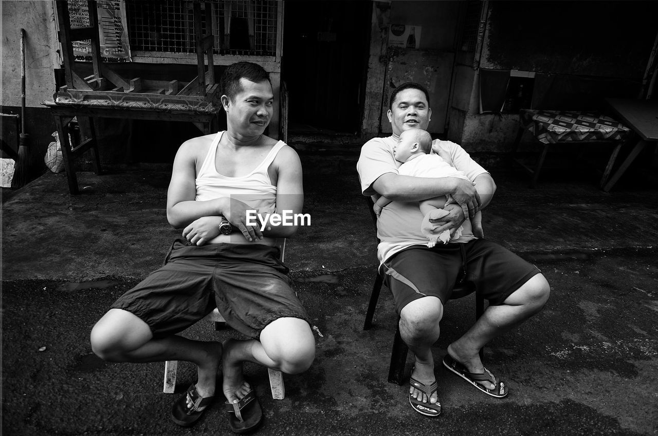 FULL LENGTH OF YOUNG COUPLE SITTING OUTDOORS