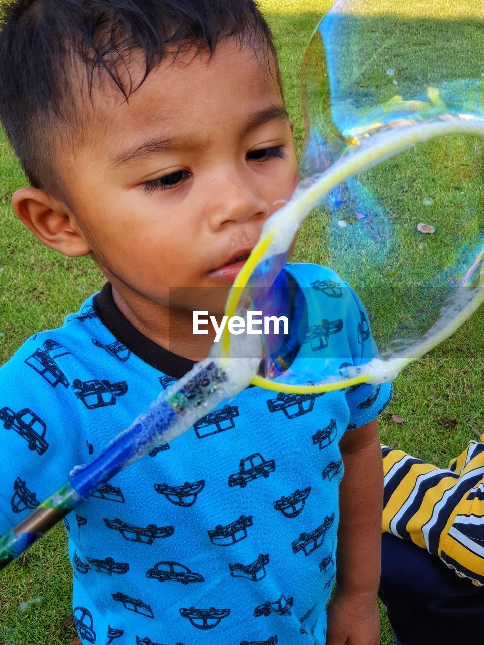 Cute boy blowing bubbles at park