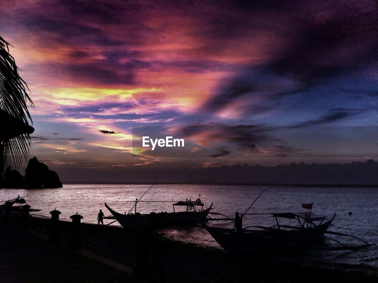 Silhouette boats moored in sea during sunset