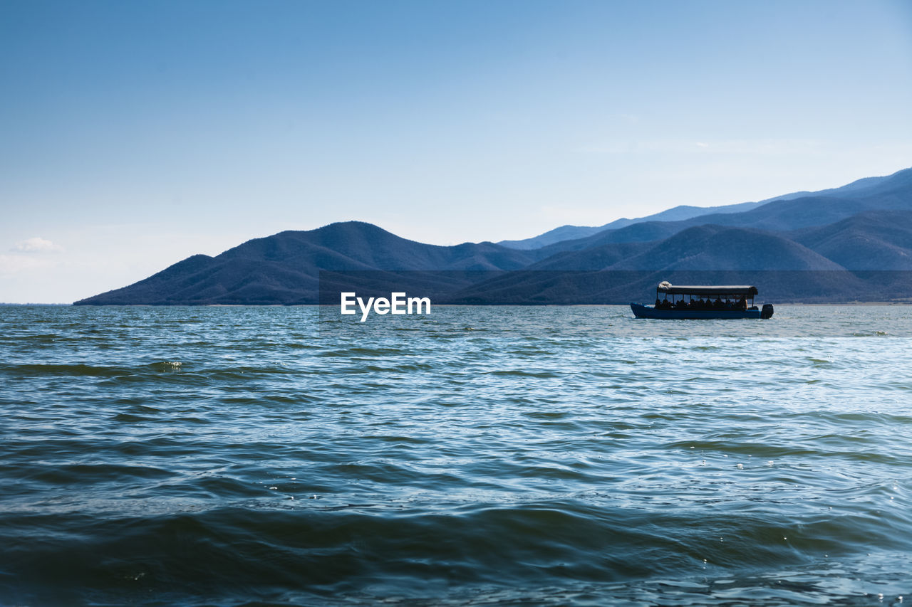 SCENIC VIEW OF SEA AGAINST MOUNTAIN RANGE