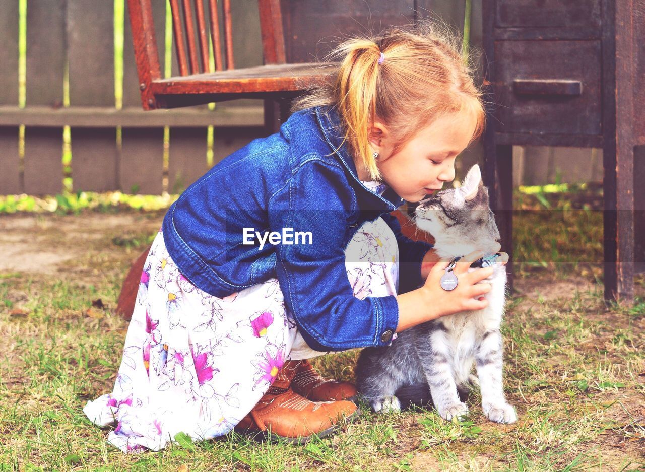 Cute girl with cat sitting on grass