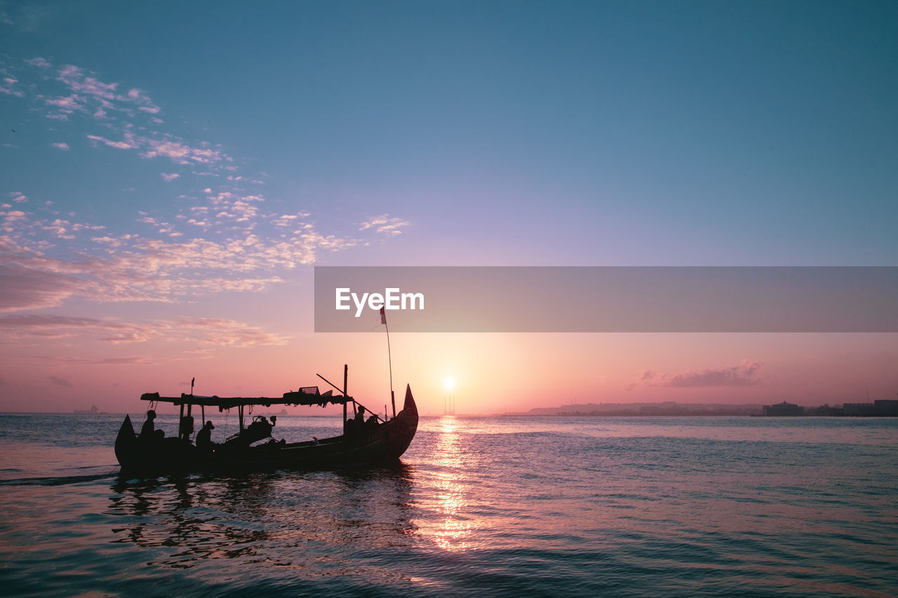 FISHING BOAT IN SEA AGAINST SUNSET SKY