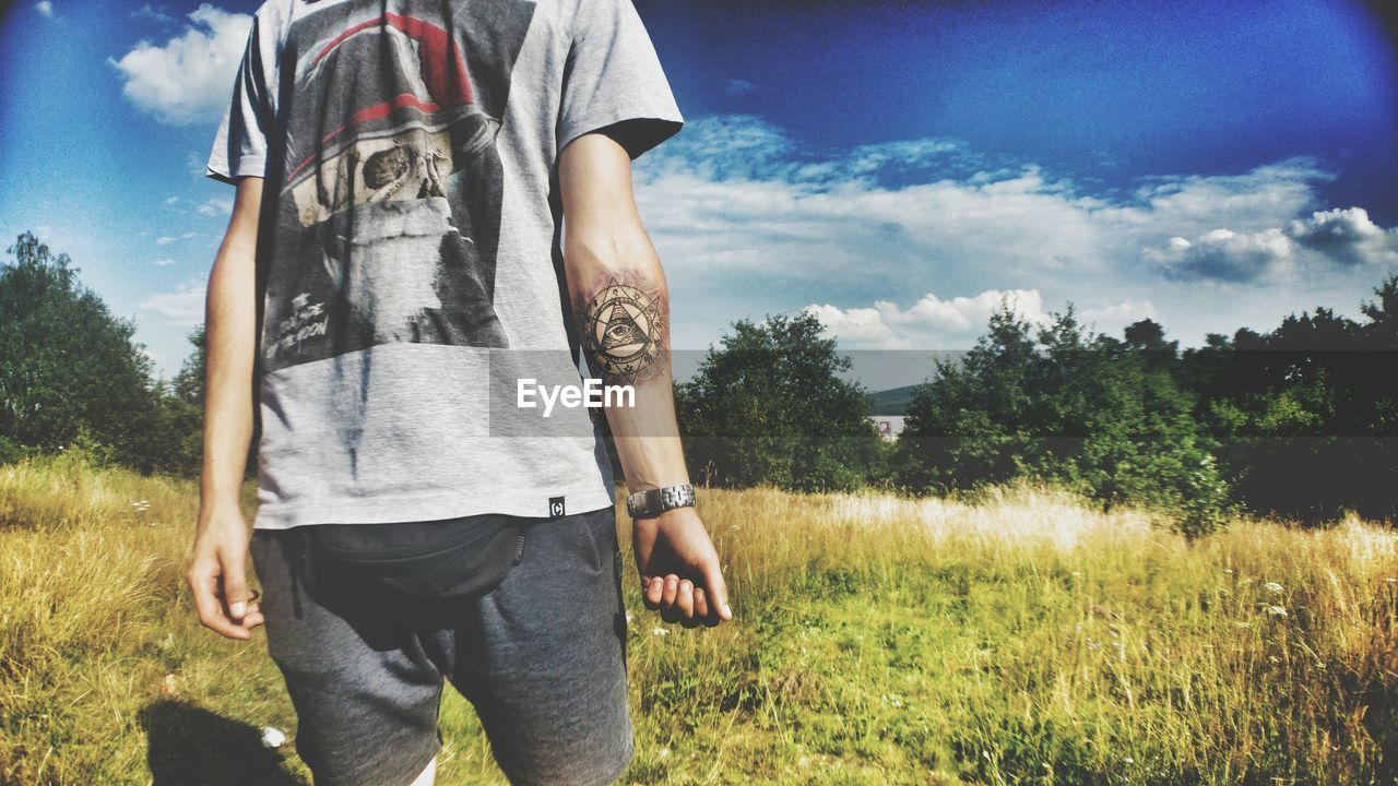 Midsection of man standing on field during sunny day