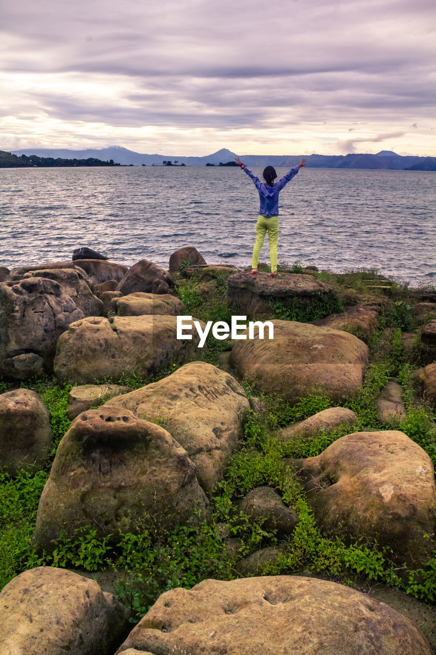 FULL LENGTH OF MAN STANDING ON ROCK AGAINST SEA