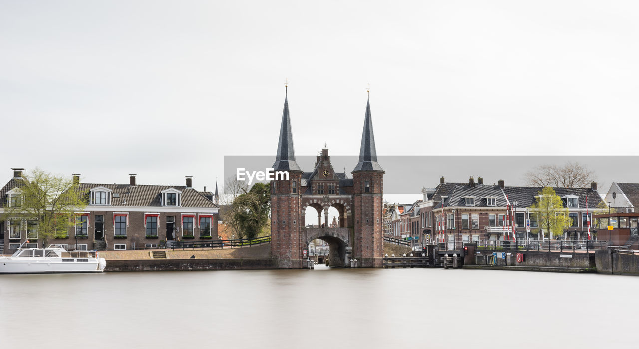 View of buildings by river against clear sky