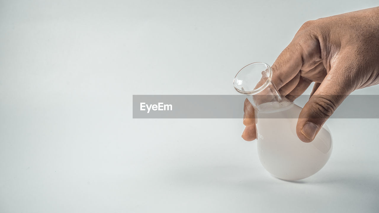 Close-up of hand holding erlenmeyer flask