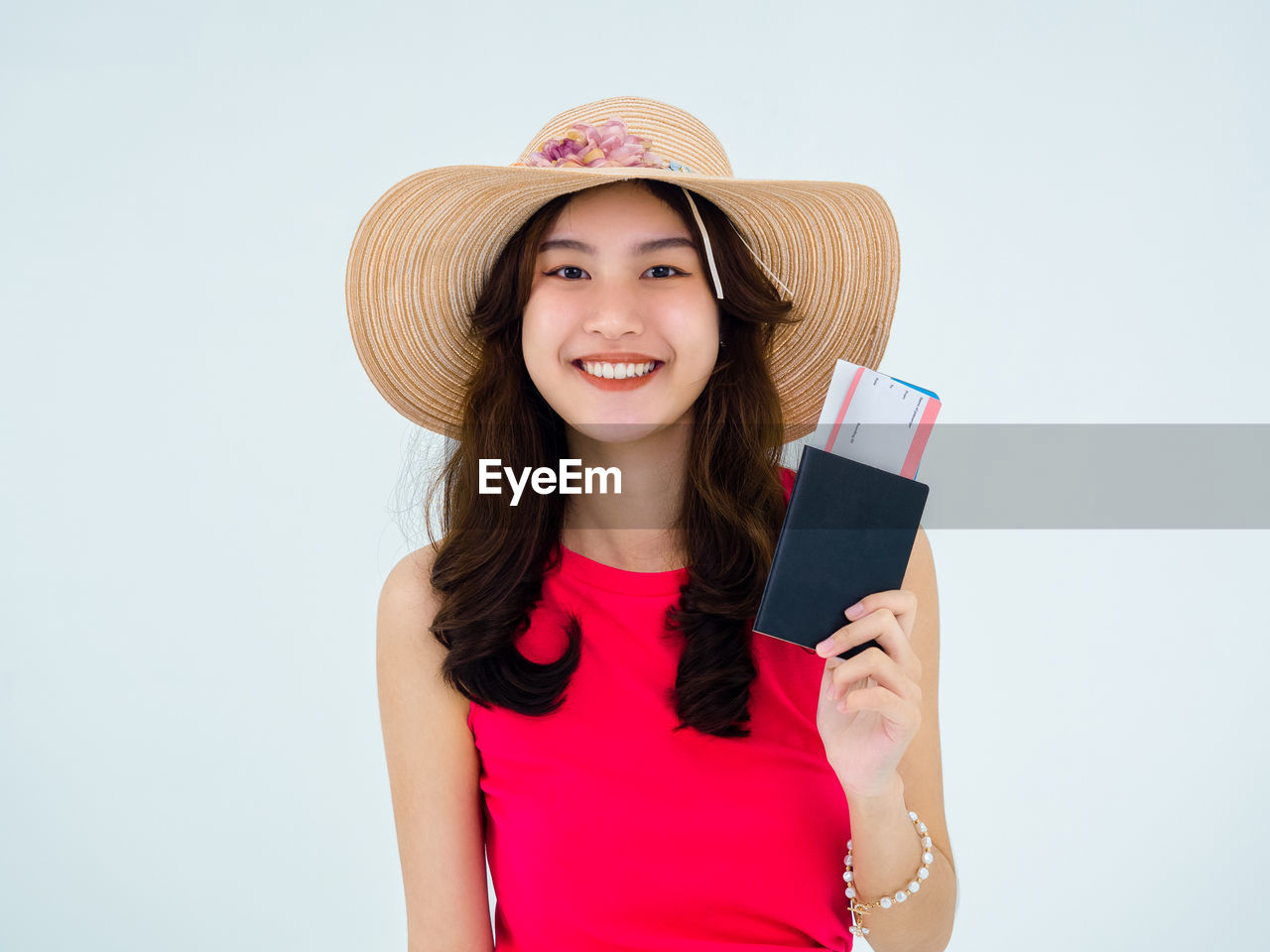 smiling, portrait, happiness, one person, women, hat, clothing, adult, studio shot, emotion, looking at camera, sun hat, pink, cheerful, holding, long hair, young adult, positive emotion, indoors, smile, teeth, waist up, person, casual clothing, front view, female, hairstyle, fashion accessory, standing, child, lifestyles, fun, copy space, enjoyment, brown hair, communication, technology, straw hat, white background, fashion