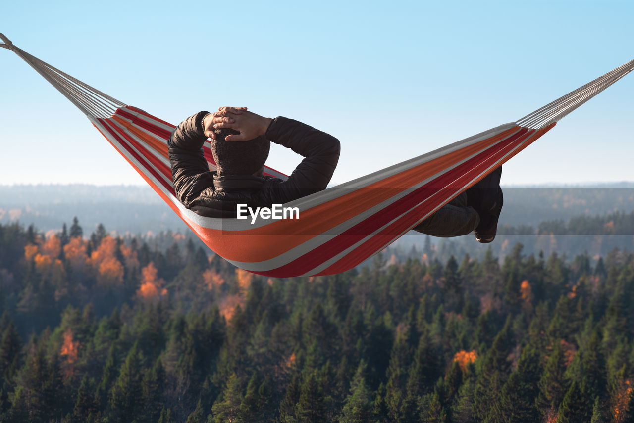Man relaxing on hammock against forest