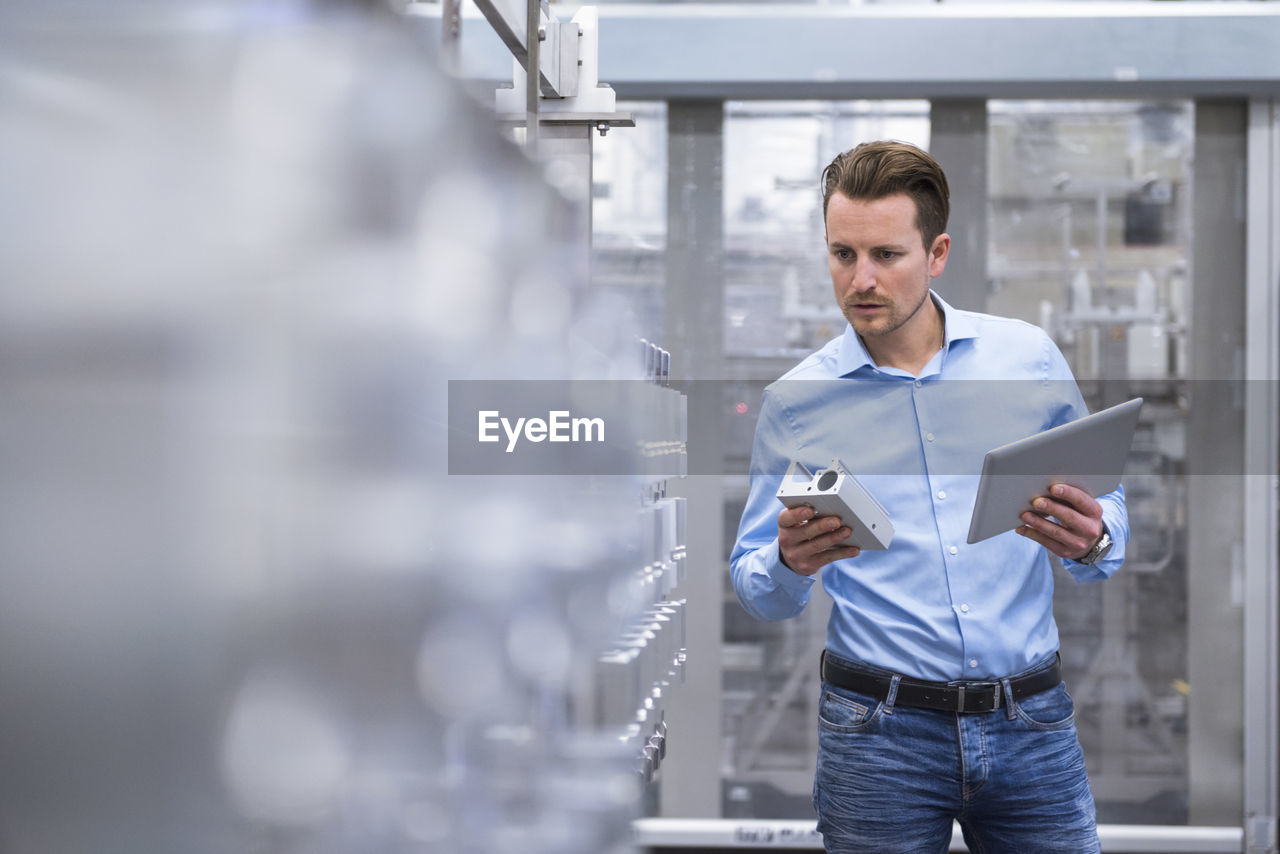 Man with tablet in factory shop floor examining products