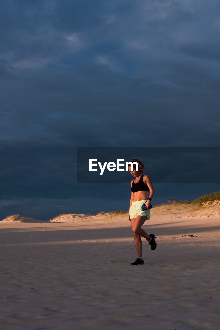 Woman stretching her leg at sunset in sand dune