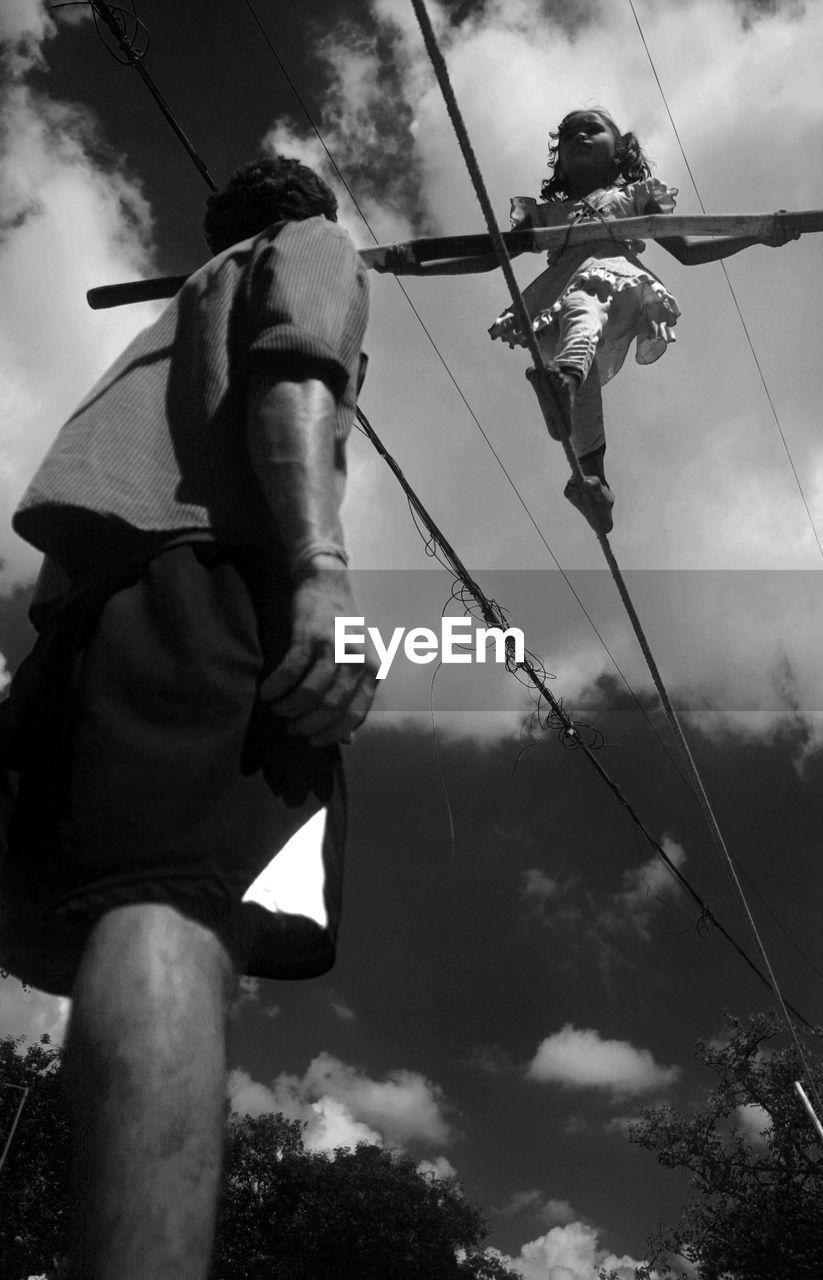 LOW ANGLE VIEW OF MEN AND ROPE AGAINST SKY