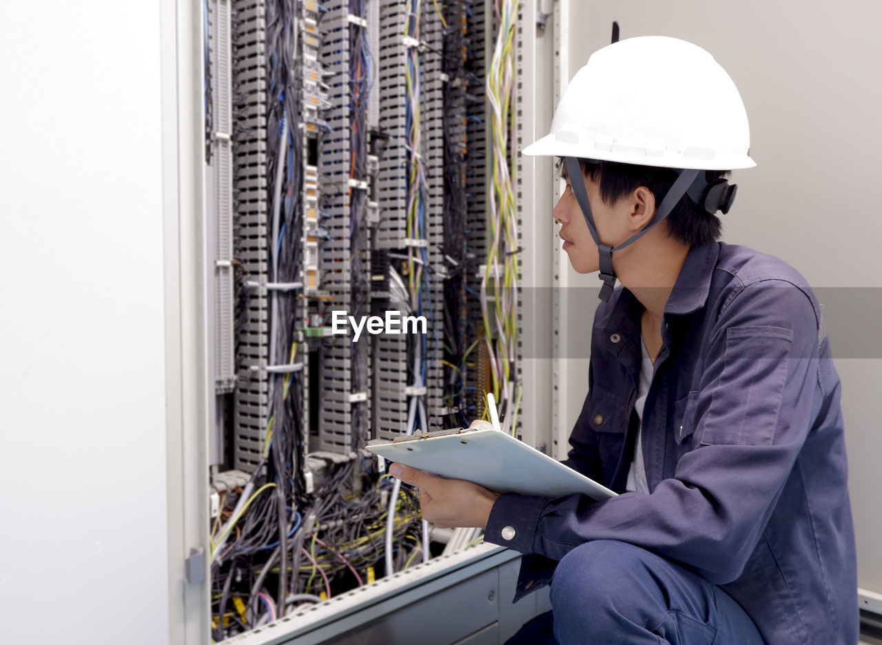 Young man examining electric fuse box