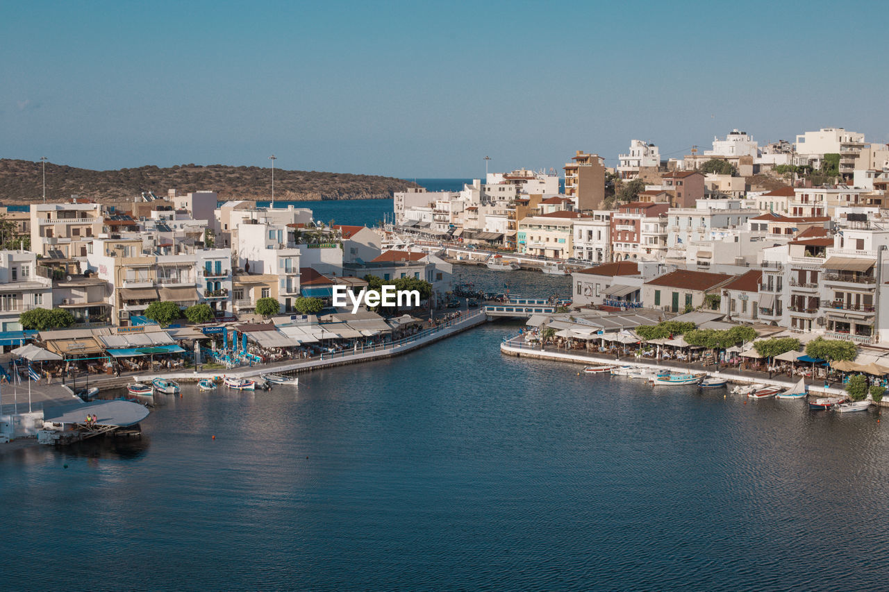 Aerial view of townscape by sea against clear sky