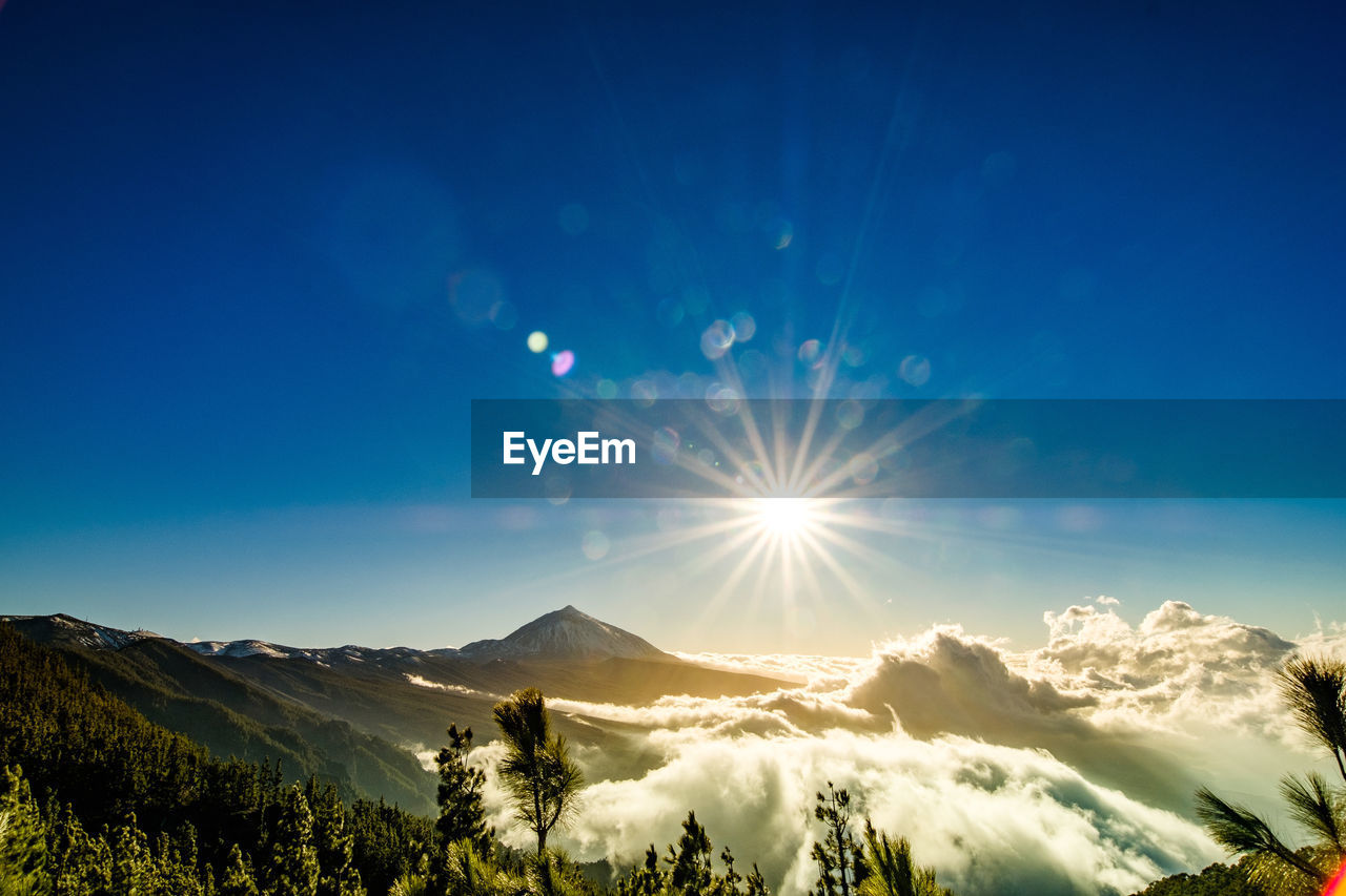 Scenic view of snowcapped mountains against bright sun