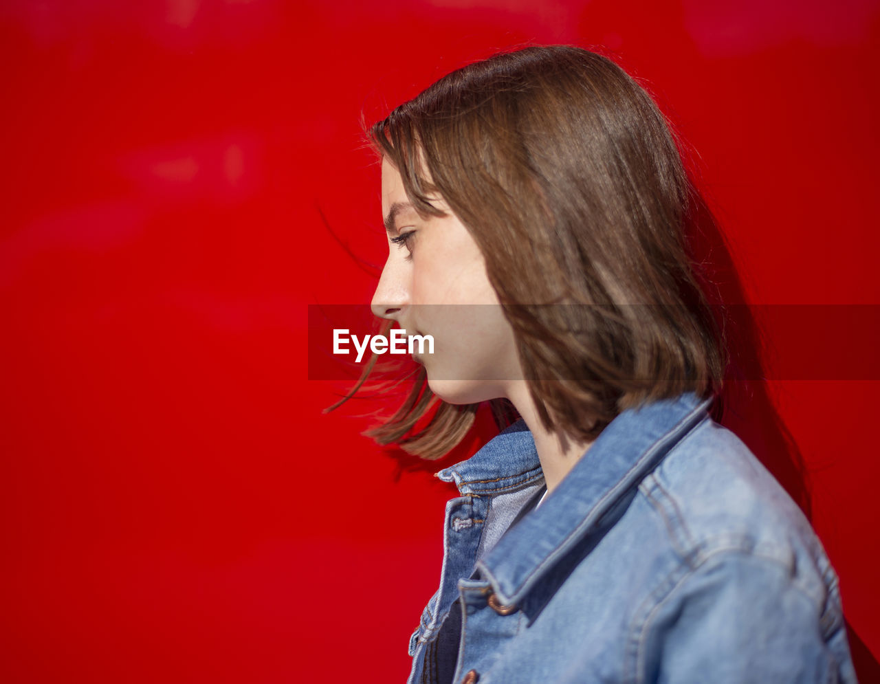 Side view of girl against red background